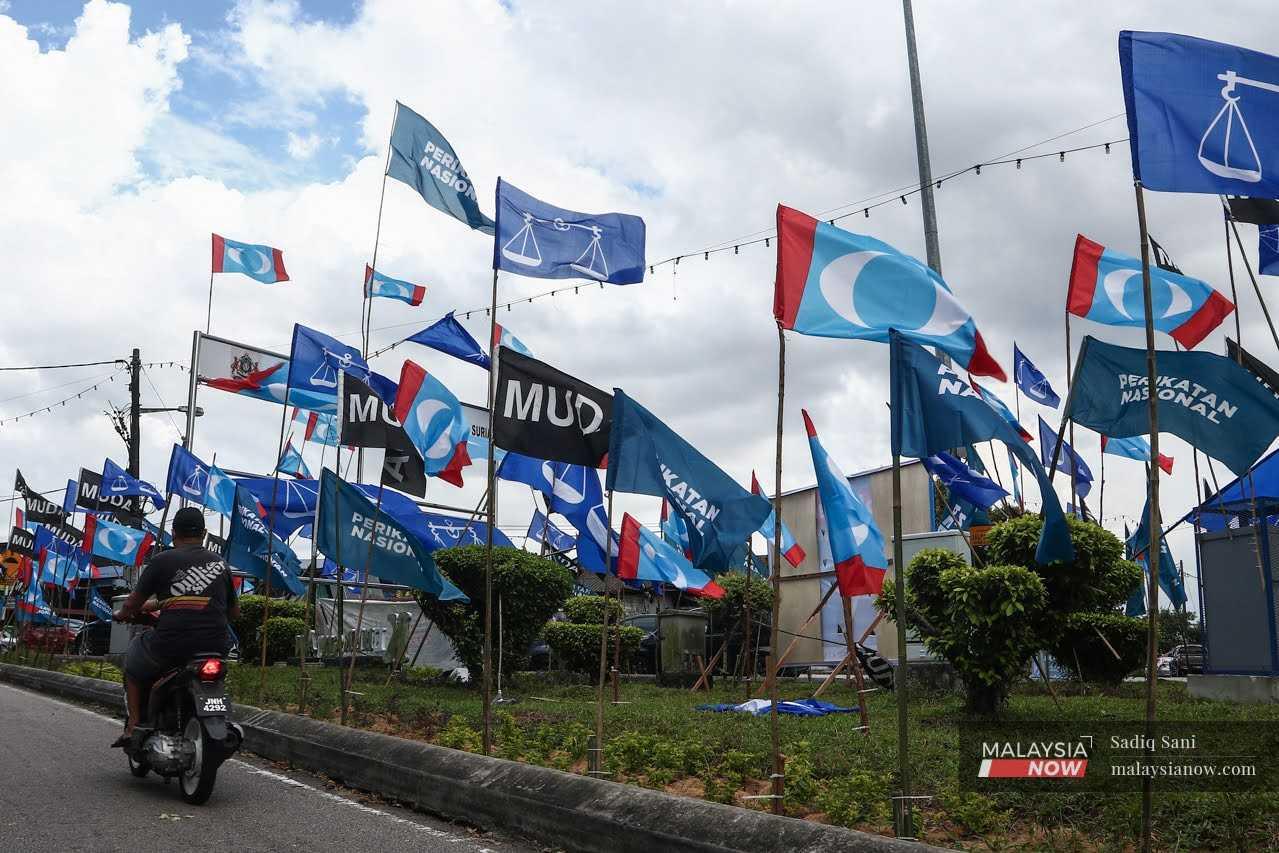 A motorcyclist rides past an array of party flags put up near Kampung Melayu Majidee ahead of the Johor state election on March 12.