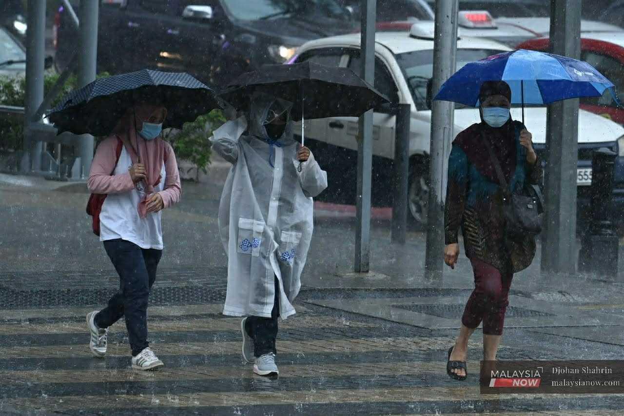 Pedestrians shield themselves from the rain with umbrellas as they cross a road in this November 2020 file photo. 
