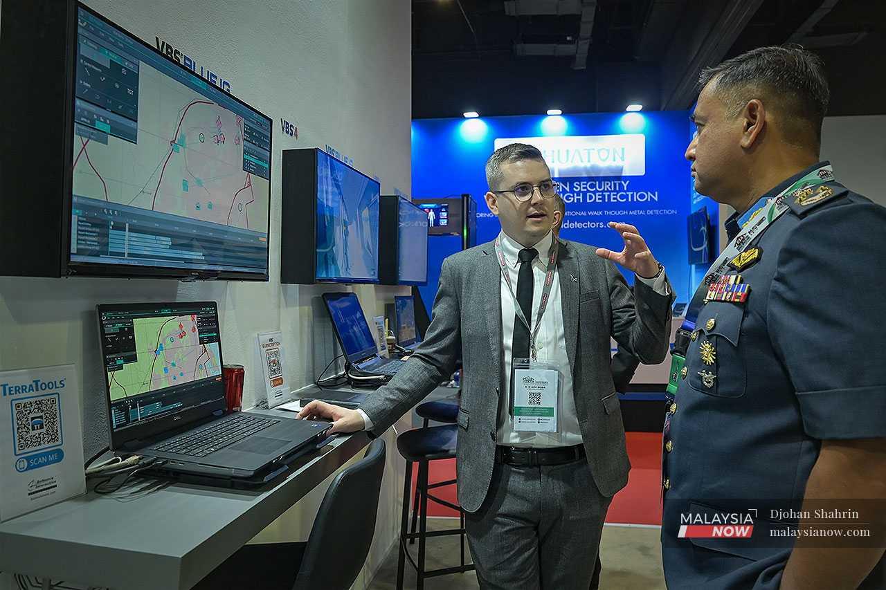 Air force man Zahani Zainal Abidin listens as a spokesman from BAE Systems explains a high-tech war simulator.