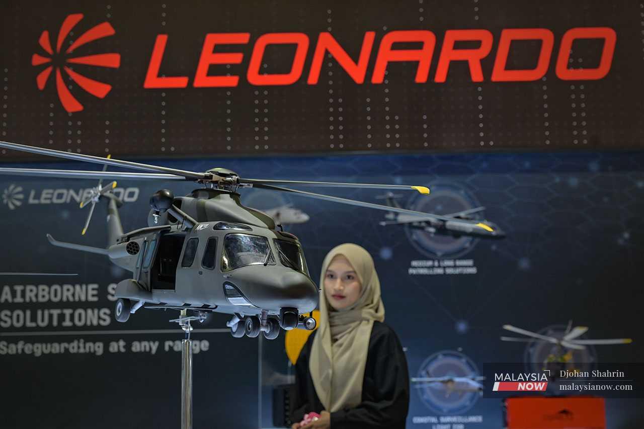 A woman examines a replica of an Italian-made Agusta AW149 war helicopter.