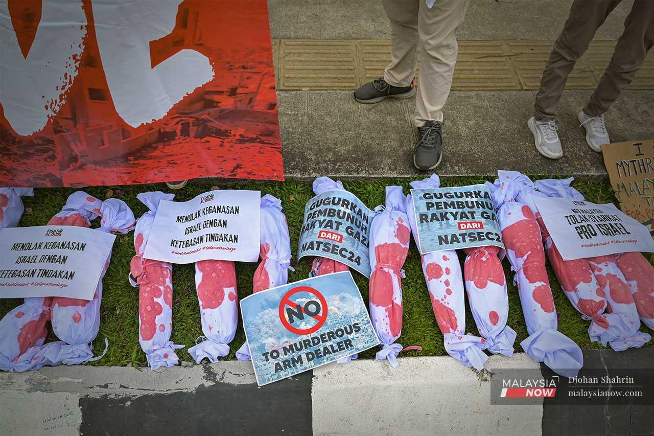 Banners and replicas of children's bodies wrapped in shrouds displayed during the protest.