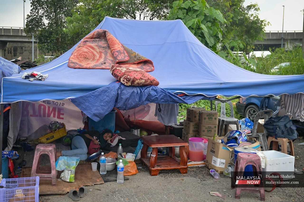 Seorang penduduk Kampung Sri Makmur berehat di bawah khemah dikelilingi barang-barang yang sempat diselamatkan ketika rumahnya dirobohkan pihak berkuasa pada 27 Mei 2024.