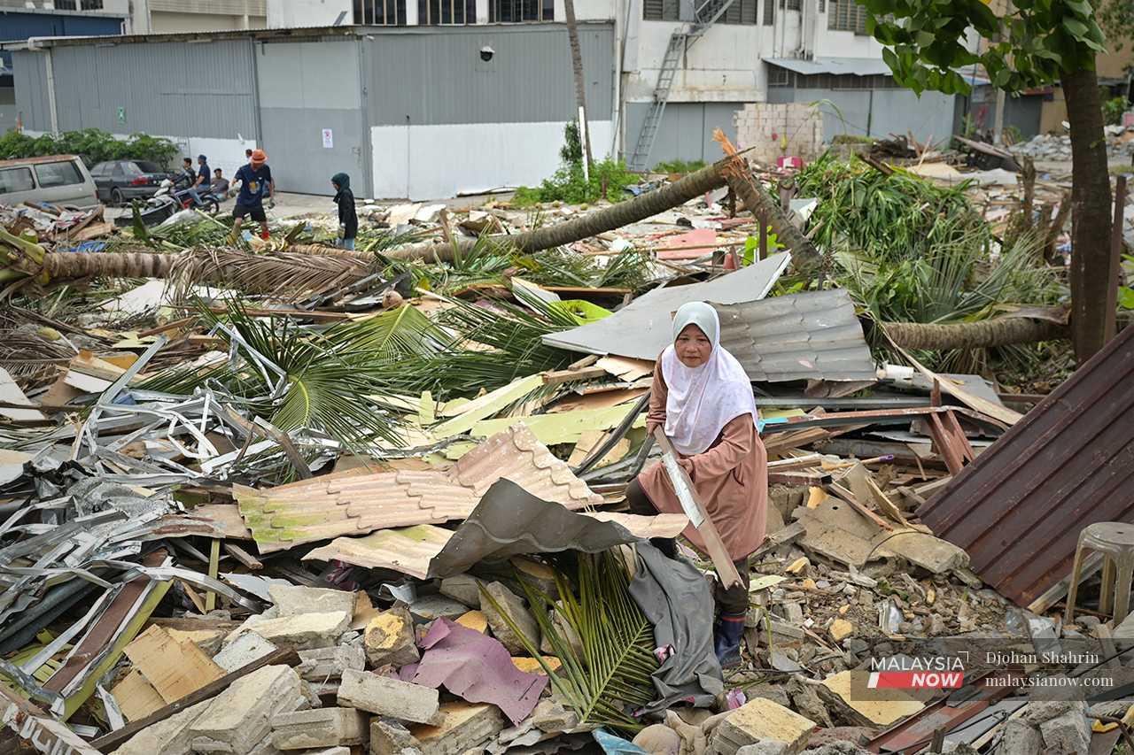 Ibu tunggal, Maimunah Jamaluddin, mengutip zink dan besi-besi dari runtuhan rumahnya untuk dijual dengan harapan mendapatkan sedikit wang belanja.