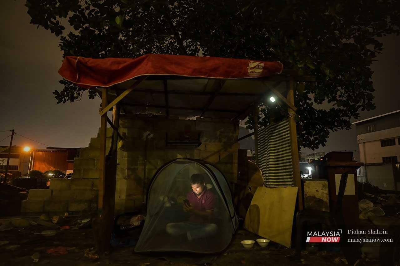 Ahmad Fariz melayari internet melalui telefon bimbit di dalam khemah yang menjadi 'rumah'.