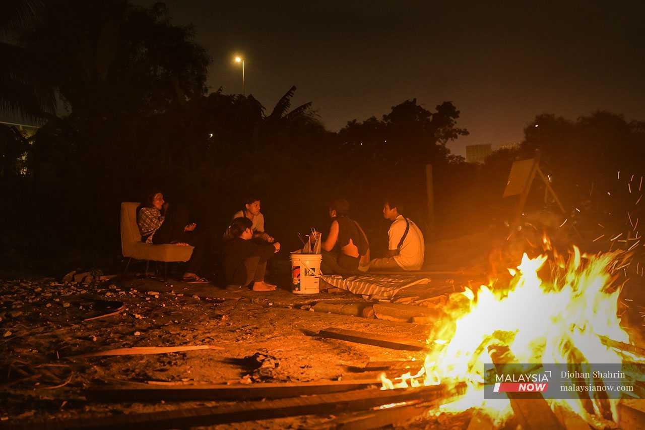 Menjelang malam, penduduk duduk berhampiran unggun api di tapak rumah yang dirobohkan sambil berbincang nasib mereka.