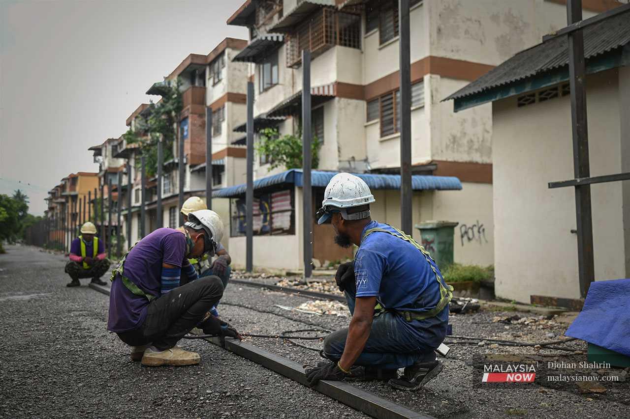 Pekerja memasang tiang seperti diarahkan pemaju di sekeliling bangunan flat.