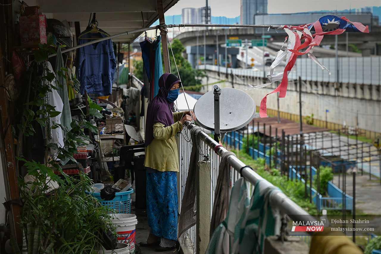 On the second floor of Block B, senior citizen Halijah Mat watches as contract workers continue putting up steel poles.