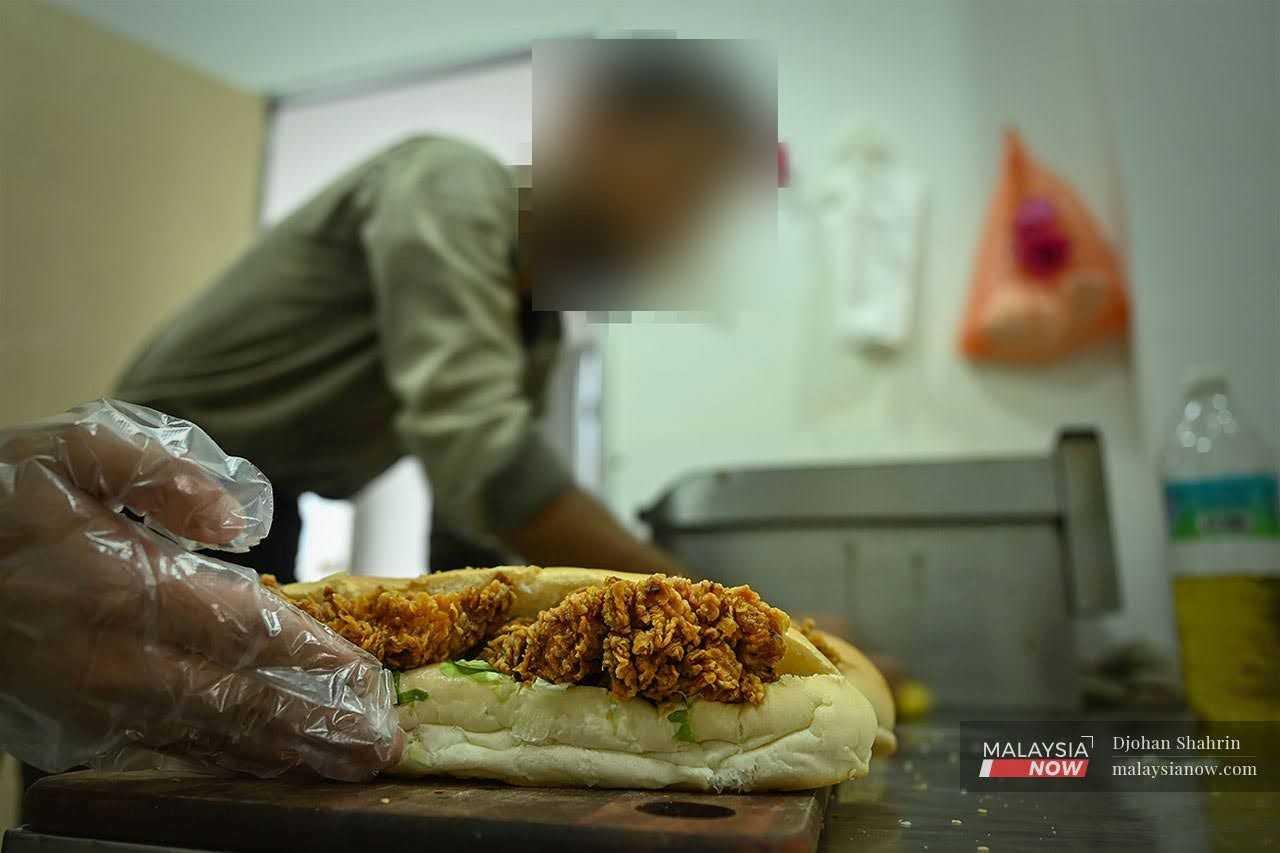 Nazeem, a Palestinian who has been living in Malaysia since 2017, prepares food in the restaurant where he works. 