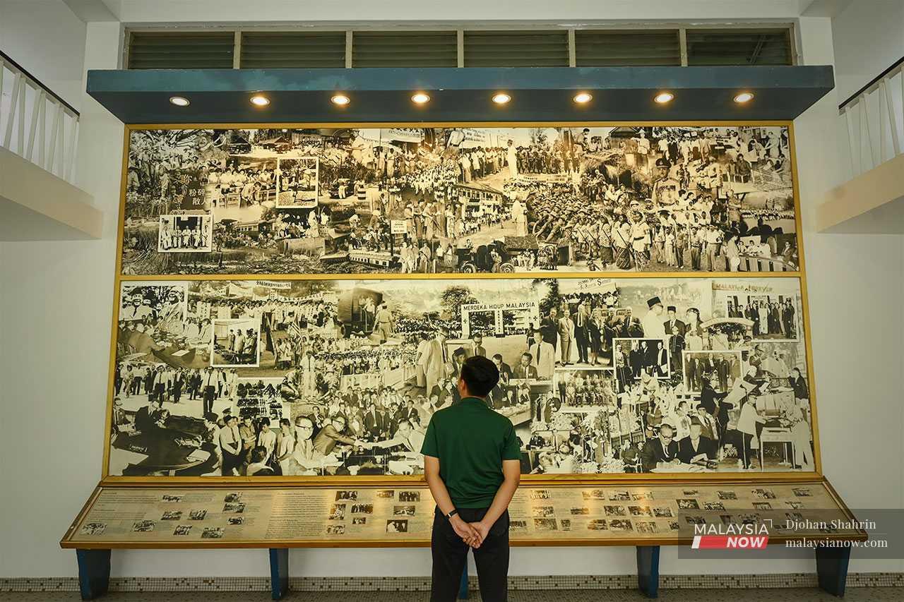 A visitor looks at a selection of images relating to the country's independence on a display board at Stadium Merdeka.