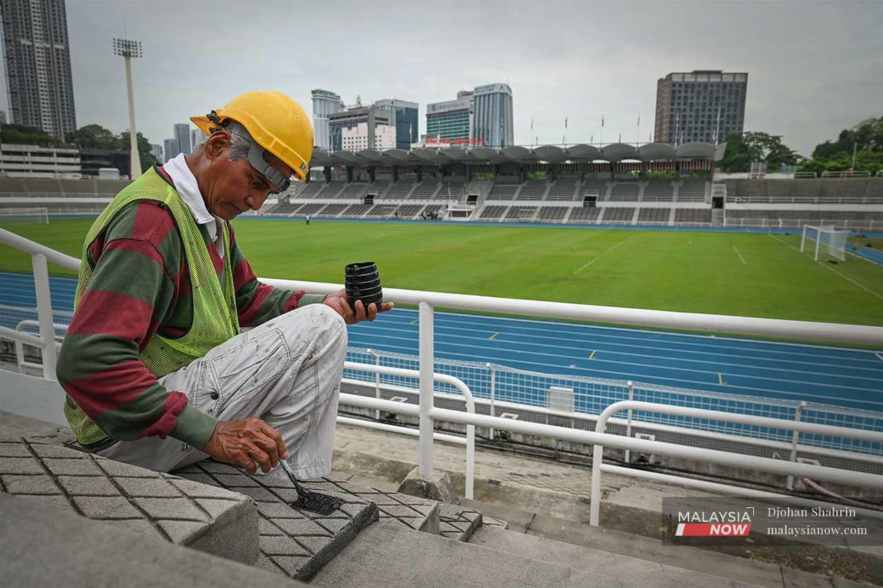 A worker marks a row at Stadium Merdeka, which has been restored to its former glory following a major refurbishment.