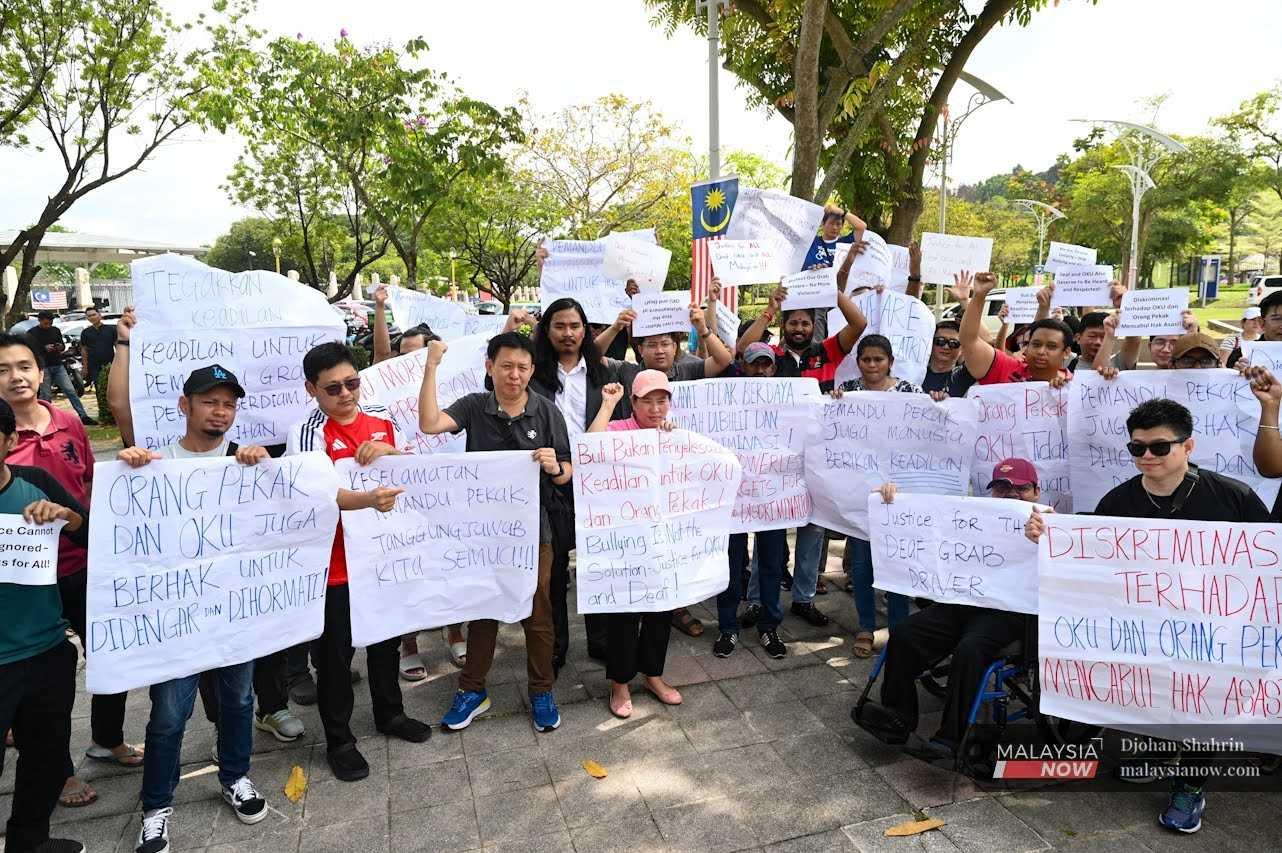 Ong Ing Keong dan peguam Zaid Malek (empat dan lima dari kiri) bersama aktivis OKU dan penyokong yang memegang sepanduk di luar Pejabat Perdana Menteri di Putrajaya.