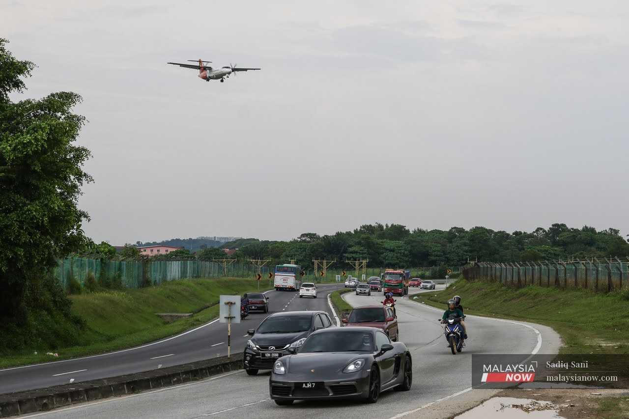 An aeroplane flies over a road on its way to Subang Airport.