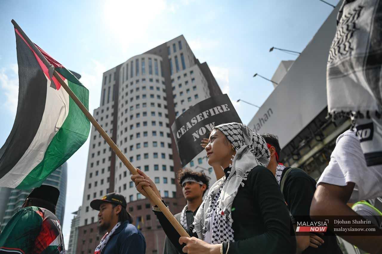 Sekumpulan peserta himpunan mengibarkan bendera Palestin tidak jauh dari Kedutaan AS di Kuala Lumpur hari ini.