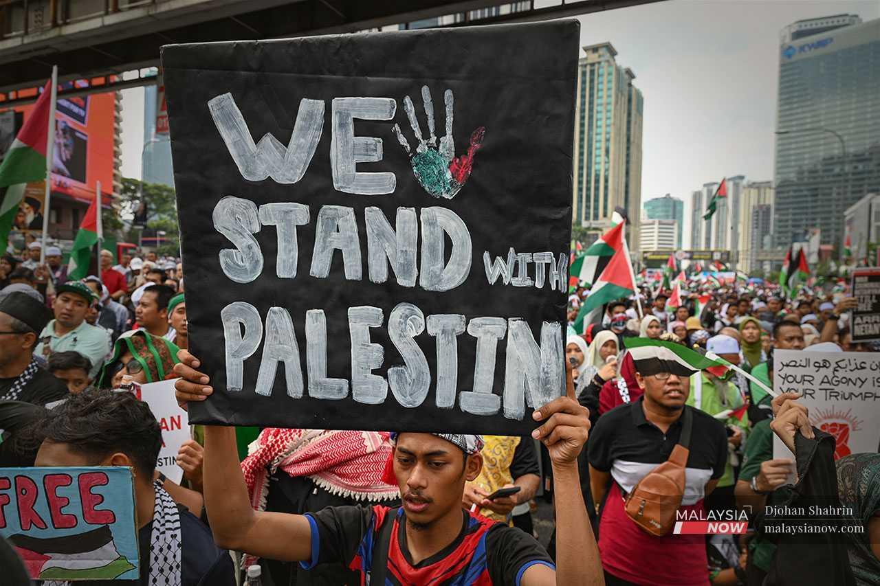 A man holds a placard to remind the Palestinian people that they will not be ignored.