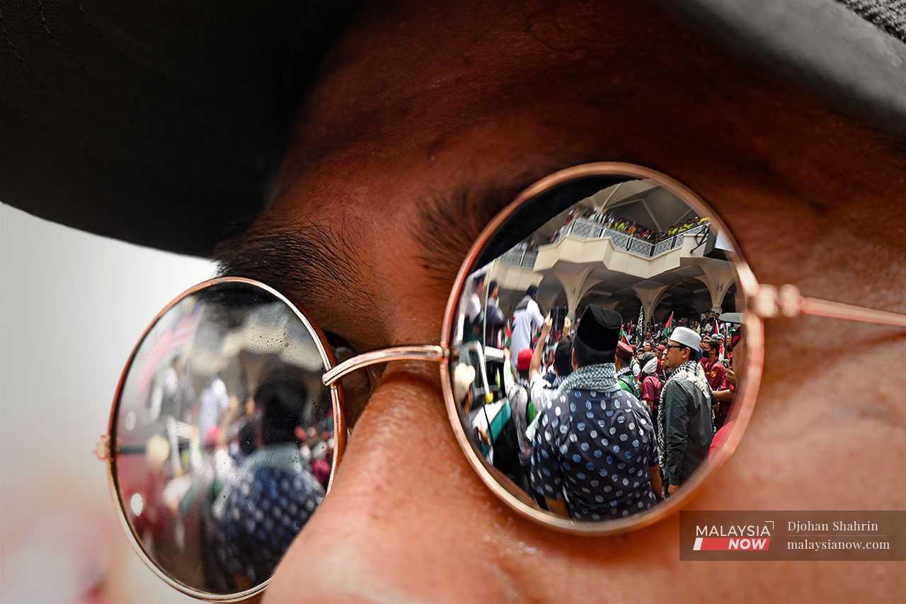 An image of the crowd listening to speeches in front of the Asy-Syakirin Mosque is reflected in the sunglasses of a protester.