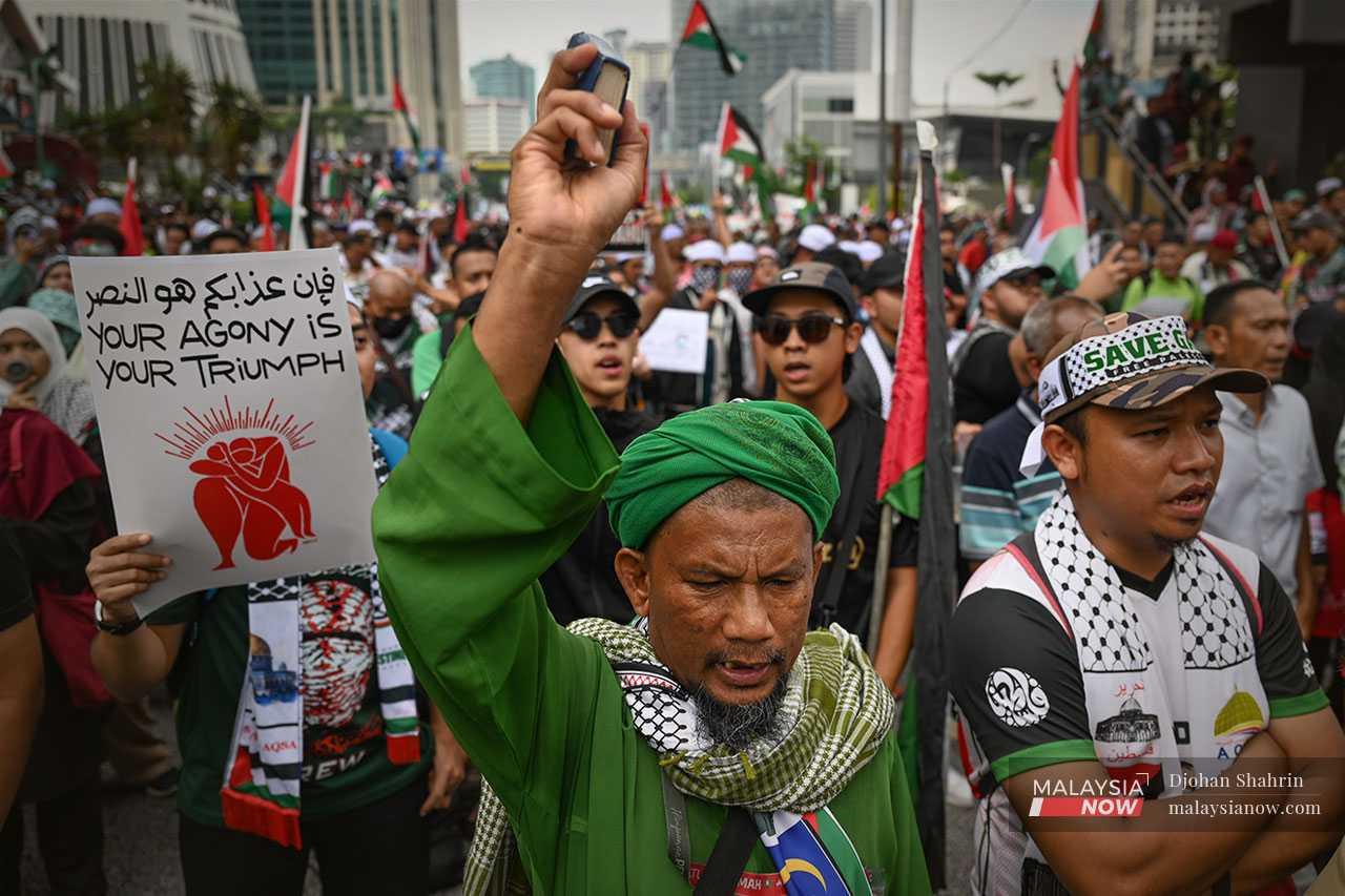 This man holds up a copy of the Quran to highlight the religious significance of Palestine, where one of the three sacred sites of Islam is located.