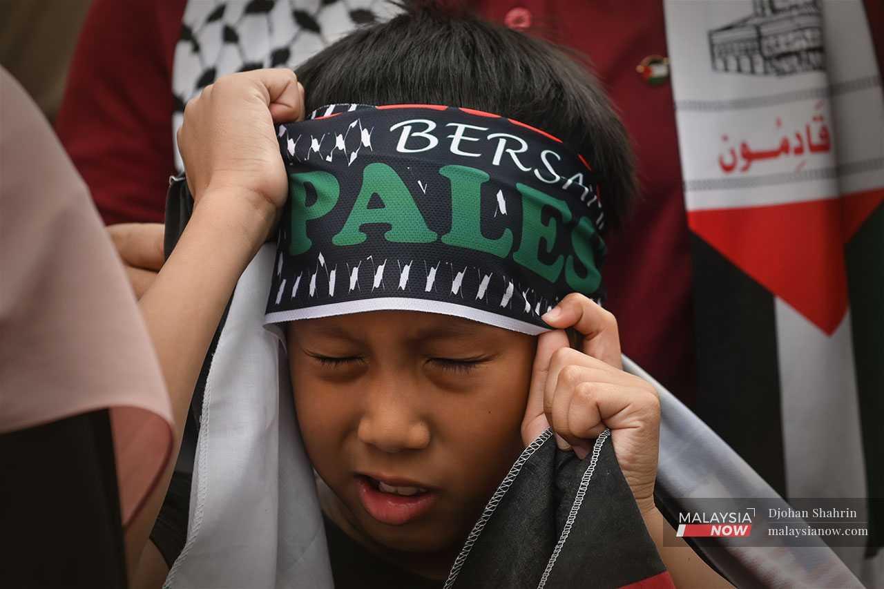 This boy fixes his Palestine mafla as he takes part in the 'Al-Aqsa Storm' rally.