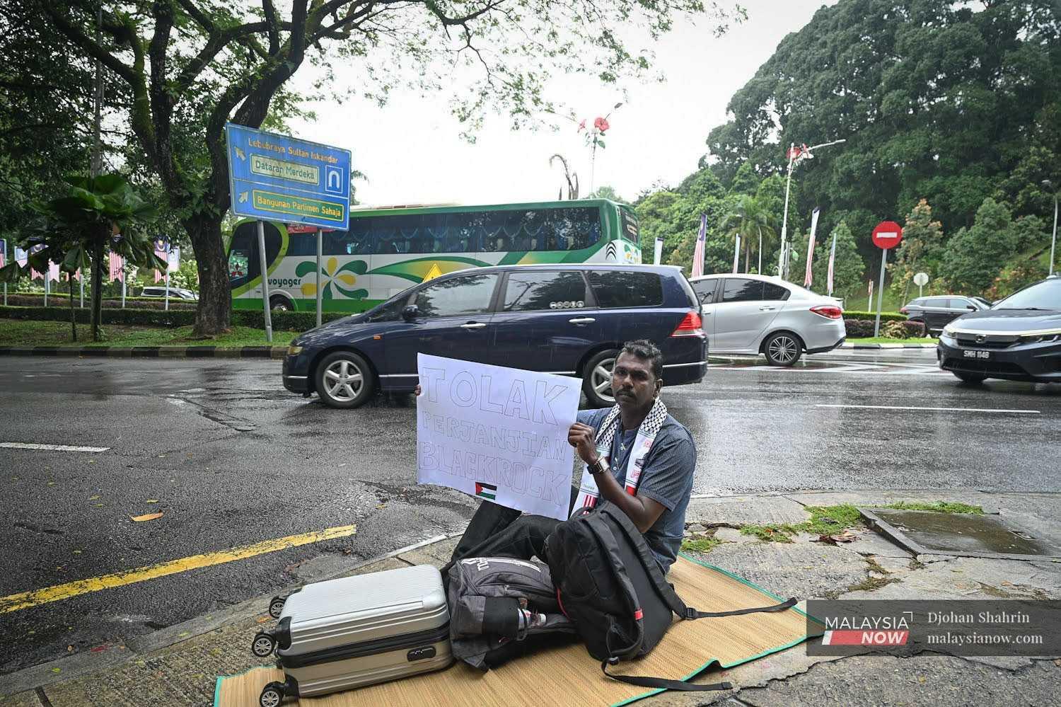 Mythreyar holds up a sign during his hunger strike near the Parliament building in July.