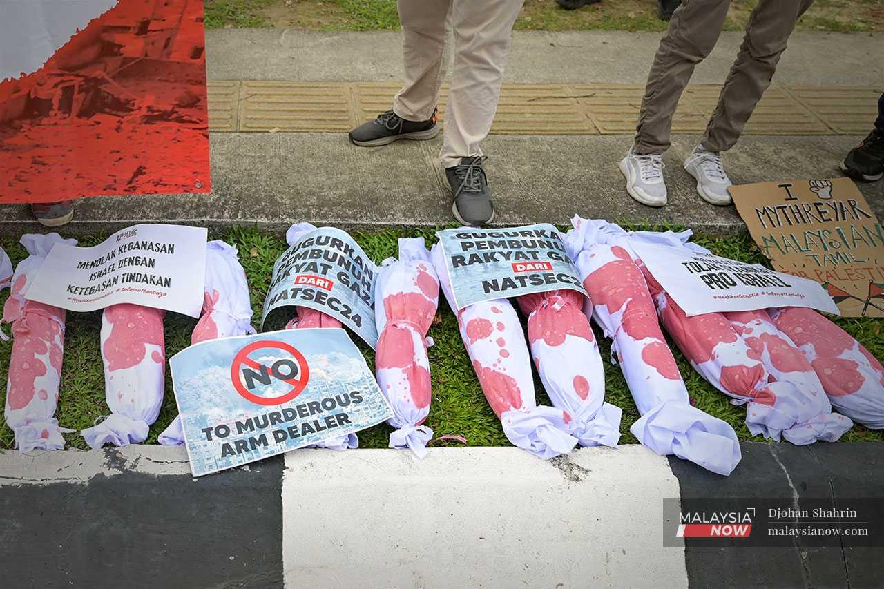 Red-stained bundles meant to represent babies lie on the ground during the demonstration.