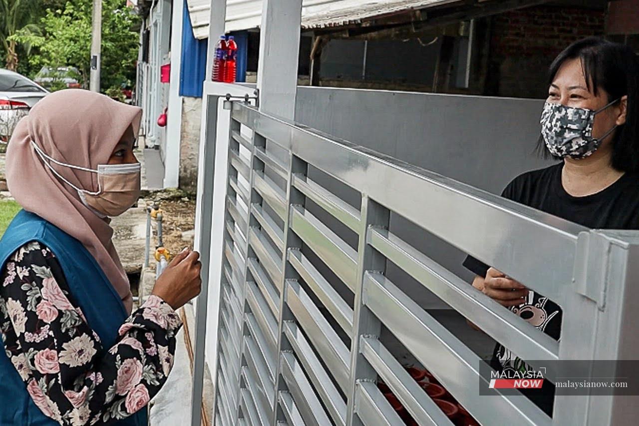 Shazani Abdul Hamid speaks to a voter during her door-to-door campaign in Ayer Hitam, Johor.