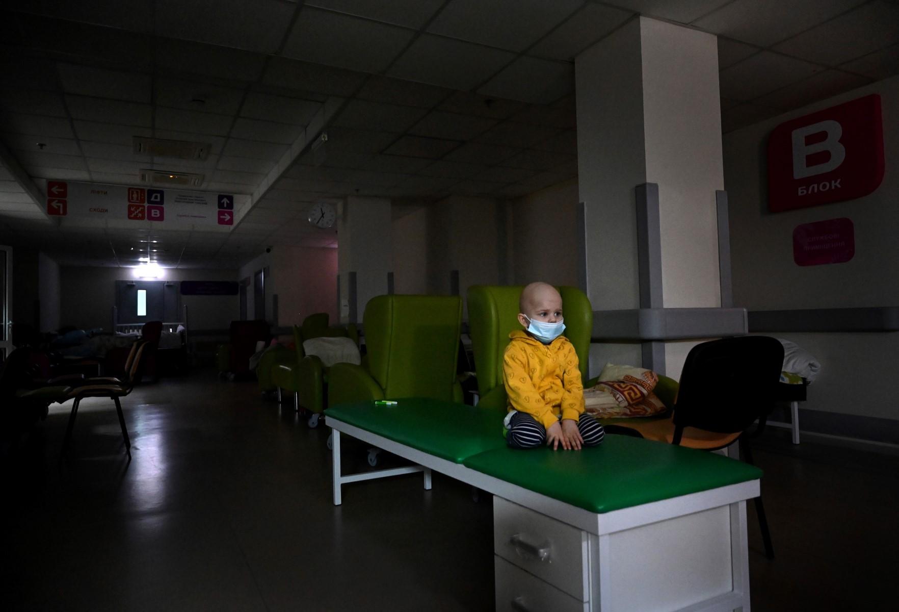 A little patient stands on a medical bench in a basement of Kyiv's central children's hospital, prior the patients' and their families' evacuation from the hospital to Poland and Germany, in Kyiv, on March 5, 10 days after Russia launched a military invasion on Ukraine. Photo: AFP