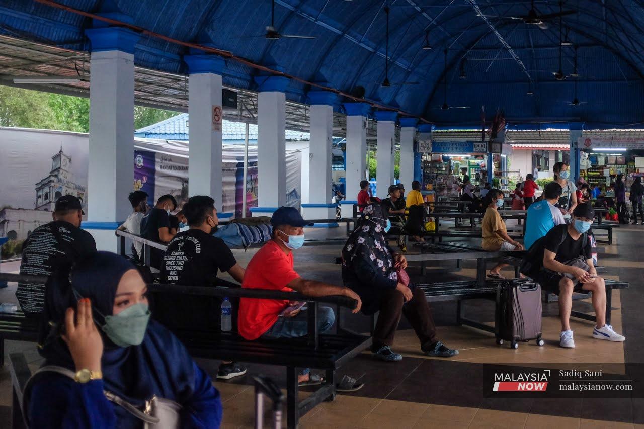 Travellers wear face masks while waiting for their bus at the Bentayan bus station in Muar, Johor.