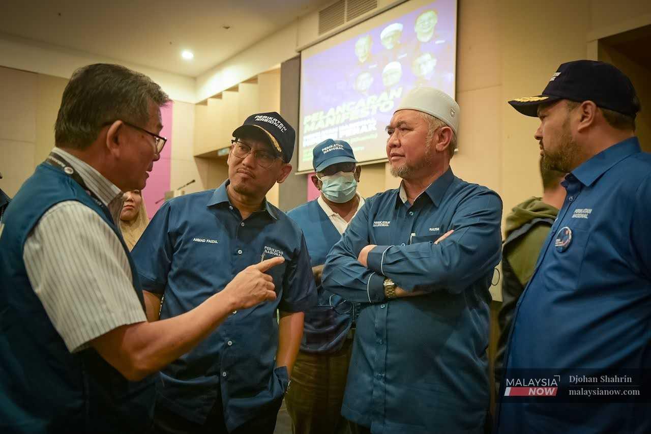 Perikatan Nasional candidate Ahmad Faizal Azumu listens during a conversation with his election team in Meru, Perak, ahead of the election this weekend.